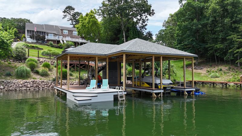 Shingle-roof boathouse with a boat lift, PWC ports and a swim platform
