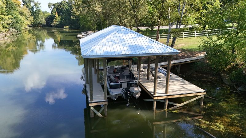 Covered pontoon slip with a white metal roof in a quiet cove