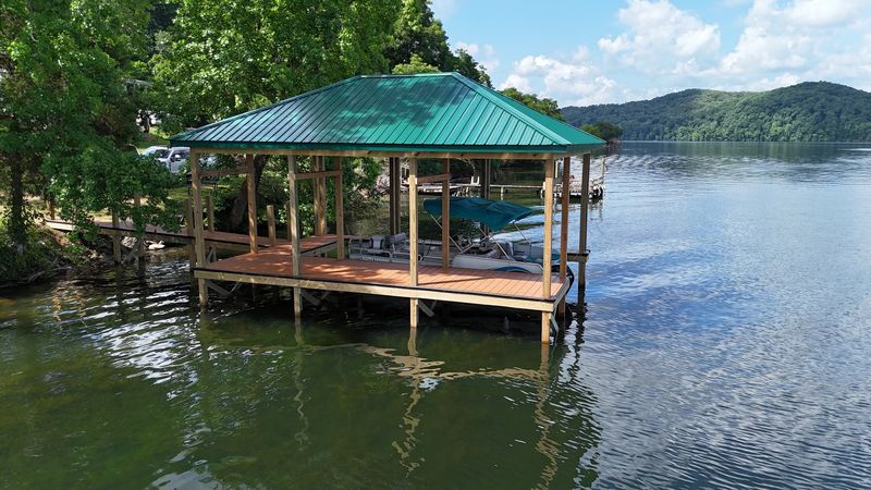 Green metal-roof covered dock with composite decking and open water beyond