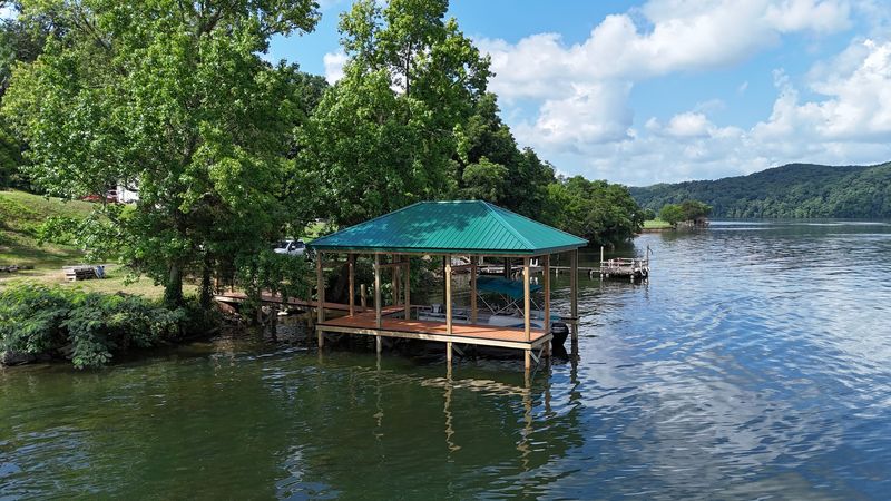 Green metal-roof covered dock on a wooded shoreline