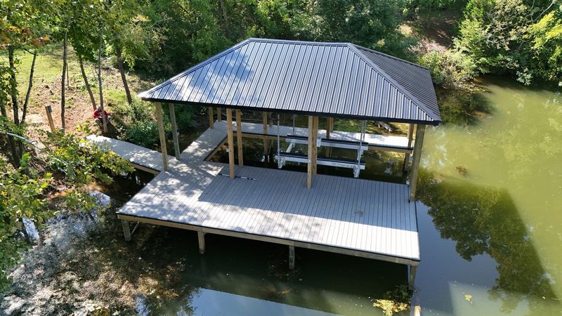 Aerial view of a covered slip with a dark hip roof and an open sun deck