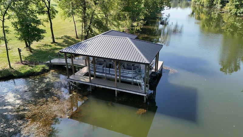 Dark metal-roof covered dock with a pontoon in a narrow cove