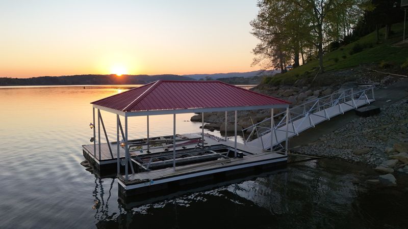 Red-roof floating dock with an aluminum gangway at sunset