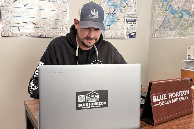 Blue Horizon team member preparing a TVA 26a permit application, with Tennessee lake maps on the office wall