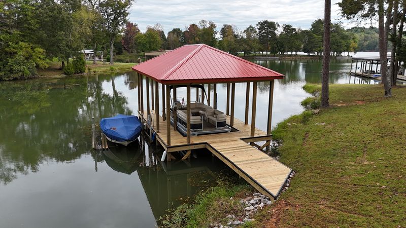 Red metal-roof open boathouse with pontoon slip on a Tennessee lake