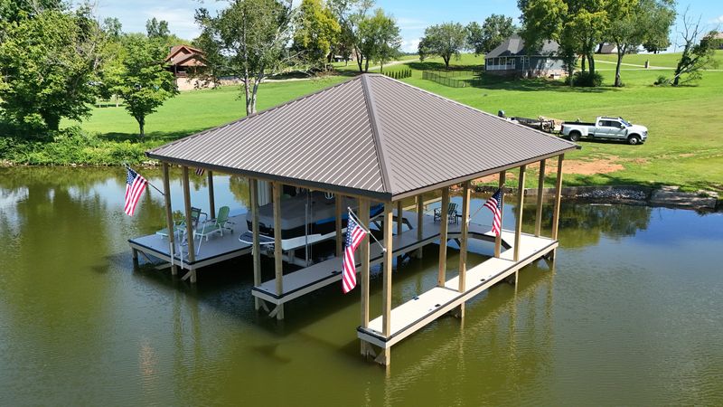 Aerial view of a brown metal-roof double-slip dock with flags