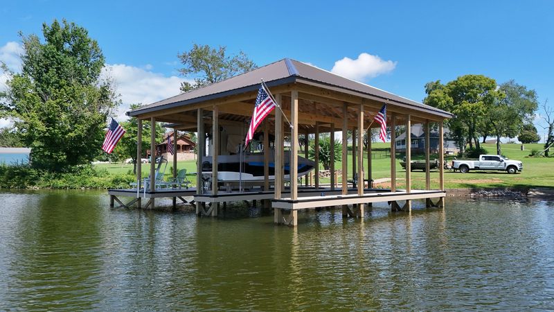Covered double-slip dock with a brown metal roof and American flags