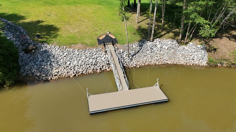 Aerial view of a floating platform dock with a gangway and riprap shoreline